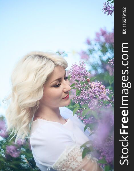 Beautiful woman in a spring garden with blooming lilacs.