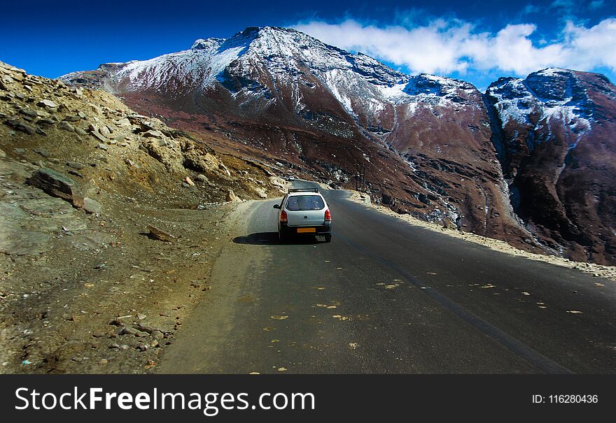 Car driving in hilly highway with green pasture and blue sky on the way to himalaya from the road,manali tourism Himachal leh ladakh, India.