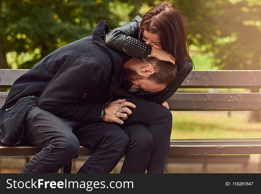 Happy modern couple, have fun on a date while cuddling on a bench in the park. Enjoying their love and nature. Happy modern couple, have fun on a date while cuddling on a bench in the park. Enjoying their love and nature.