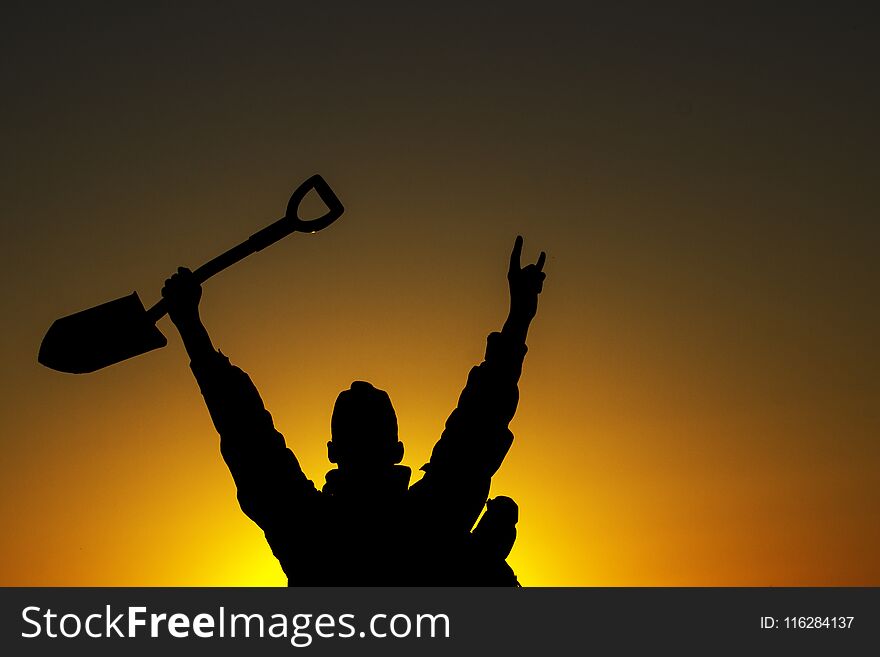 Tourist with a sapper shovel against the backdrop of a bright sky at dawn concept of outdoor activities