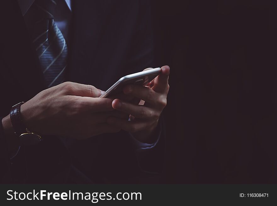 Businessman hand using smartphone in black background