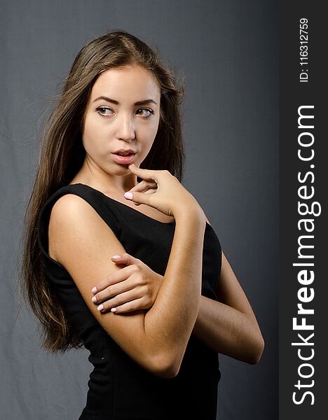 Young beautiful girl in dress posing in Studio on dark background