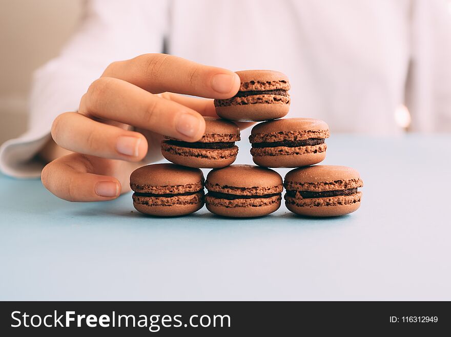 Woman Placing Macaroons On Heap On Blue Table