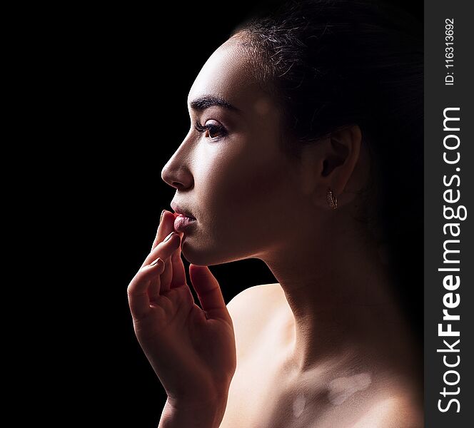 Profile portrait of beautiful woman with vitiligo. Over black background.