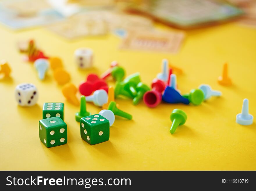 The concept of board games. Dice, chips and cards on a yellow background