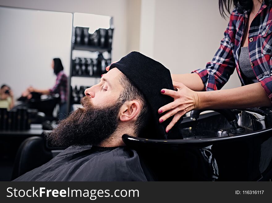 Close up image of female hairdresser washing bearded men`s hair before haircut in a saloon. Close up image of female hairdresser washing bearded men`s hair before haircut in a saloon.