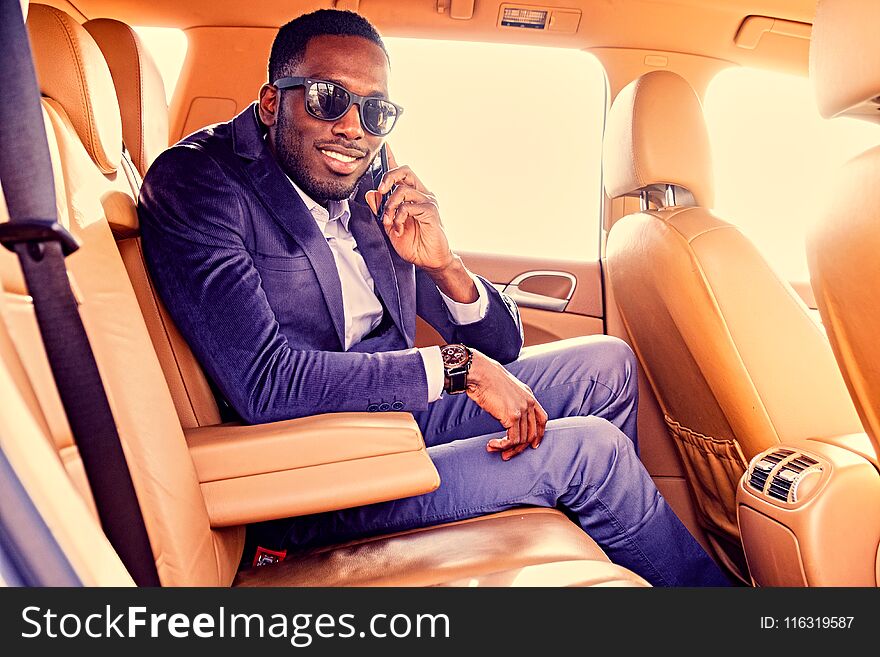 Portrait of black American elegant male talks on smartphone in a car. Filtered warm toned image. Portrait of black American elegant male talks on smartphone in a car. Filtered warm toned image.