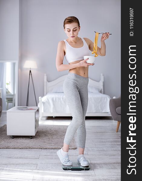 Weight control. Nice young woman standing on weights while preparing for work. Weight control. Nice young woman standing on weights while preparing for work