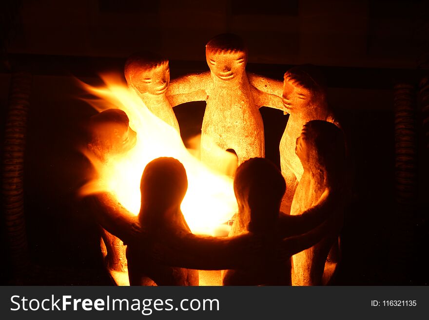 Candlestick in the form of embracing little men, burning fire.