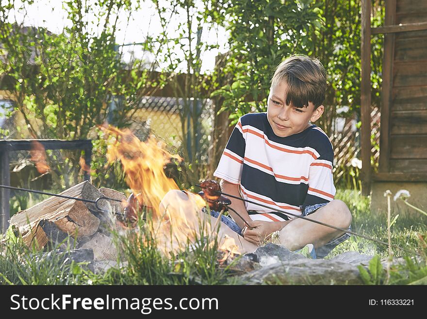 Children enjoy campfire. Boy toasting sausages on the garden. Children enjoy campfire. Boy toasting sausages on the garden.