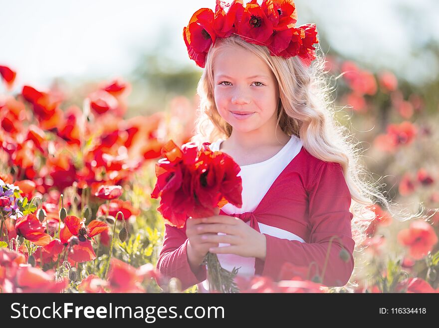 Pretty blonde child girl is wearing wreath from red flowers in poppy meadow