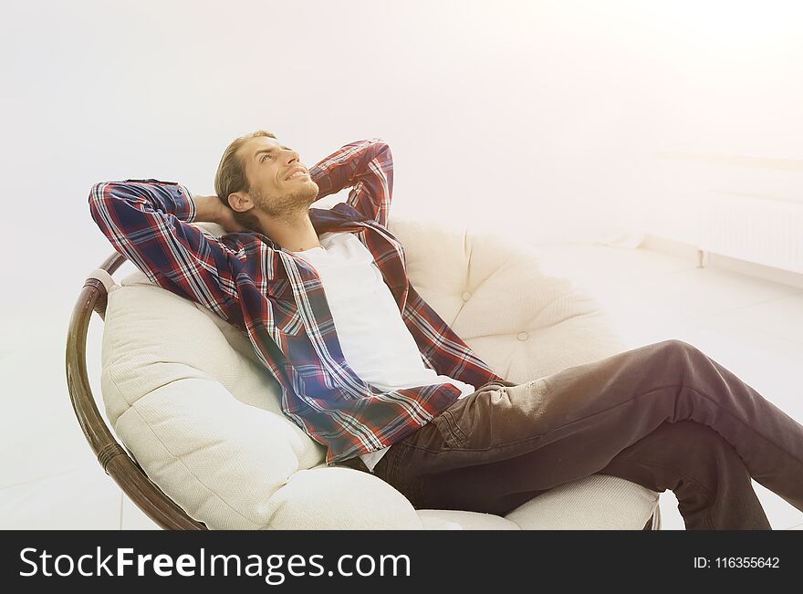 Serious guy rests sitting and dreaming in a large comfortable chair.