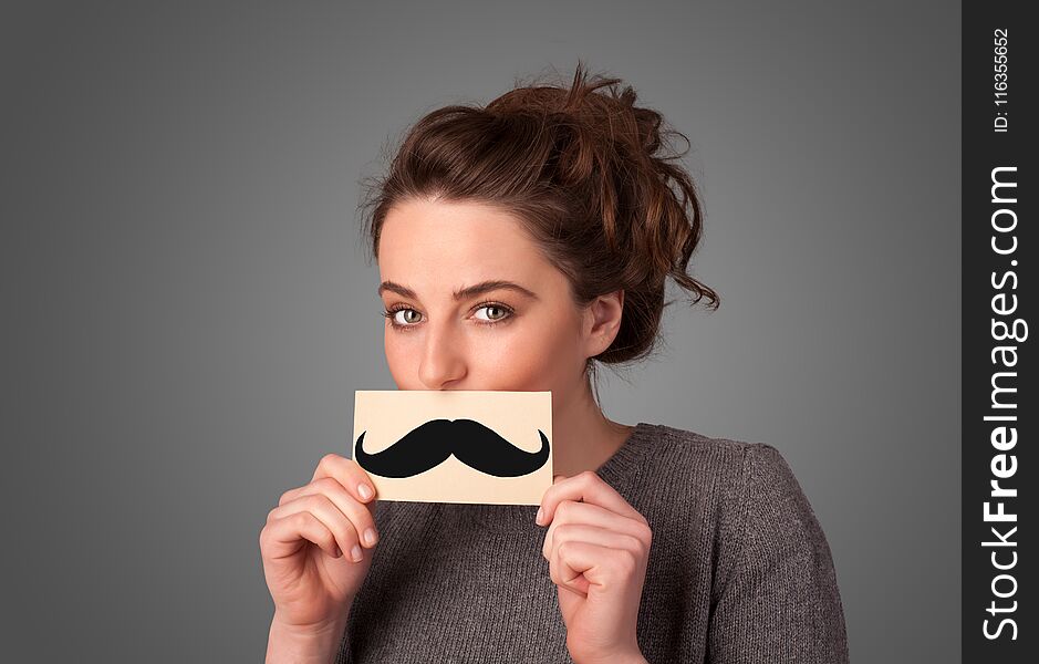 Happy cute girl holding paper with mustache drawing on gradient background