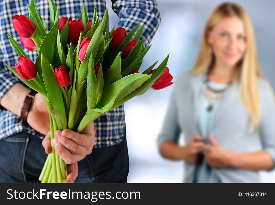 Picture of young man surprising woman with flowers.
