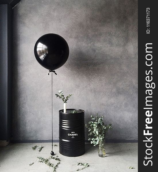 Grayscale Photography of Balloon Beside Chanel Metal Barrel