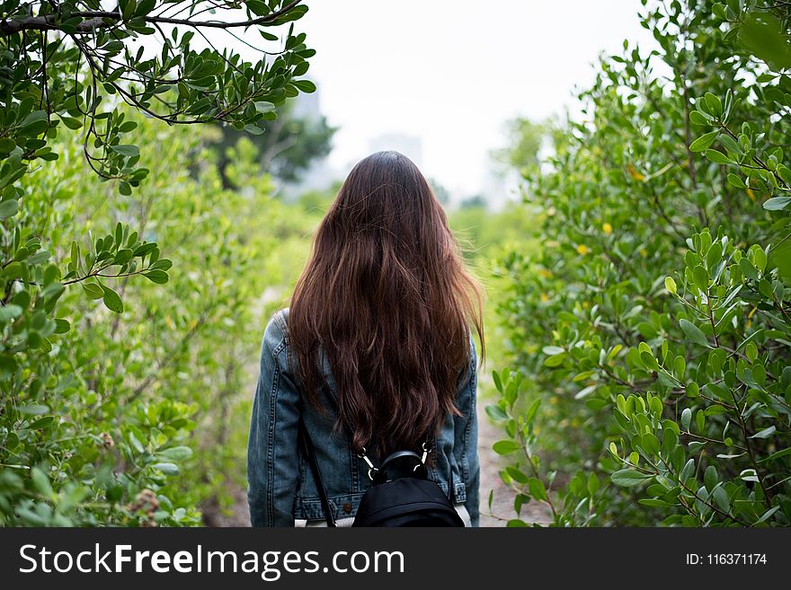 Woman In Gray Denim Jacket In The Middle Of Bushes