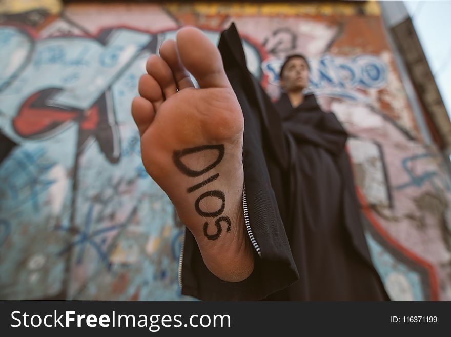 Person Wearing Black Robe With Sign On Foot