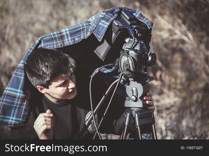 Photo of Man Setting Up Dslr Camera on Tripod