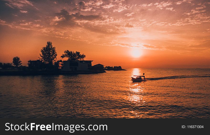 Silhouette Of House And Trees By Water During Golden Hour