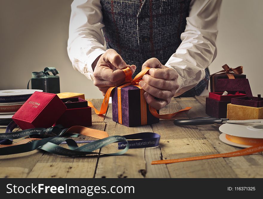 Person Tying Ribbon on Purple Gift Box
