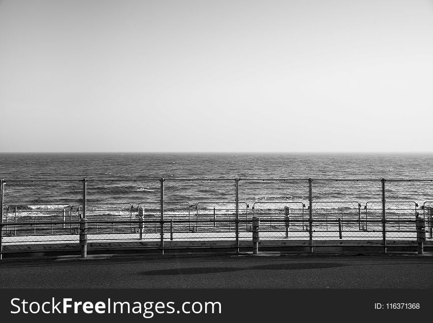 Grayscale Photography of Fence Beside Ocean