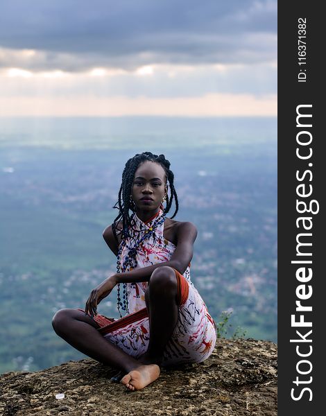 Woman Sitting On Ground And Village At Distance