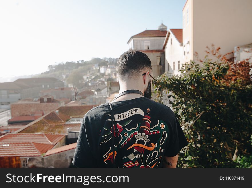 Man Wearing Black T-shirt Standing Near White Concrete Houses