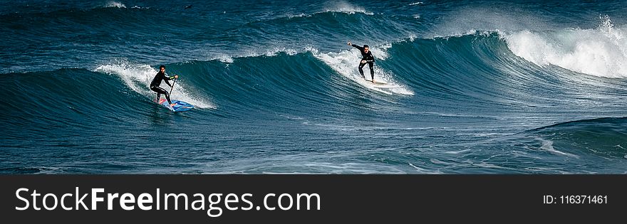 Two Surfers Gliding On Body Of Water