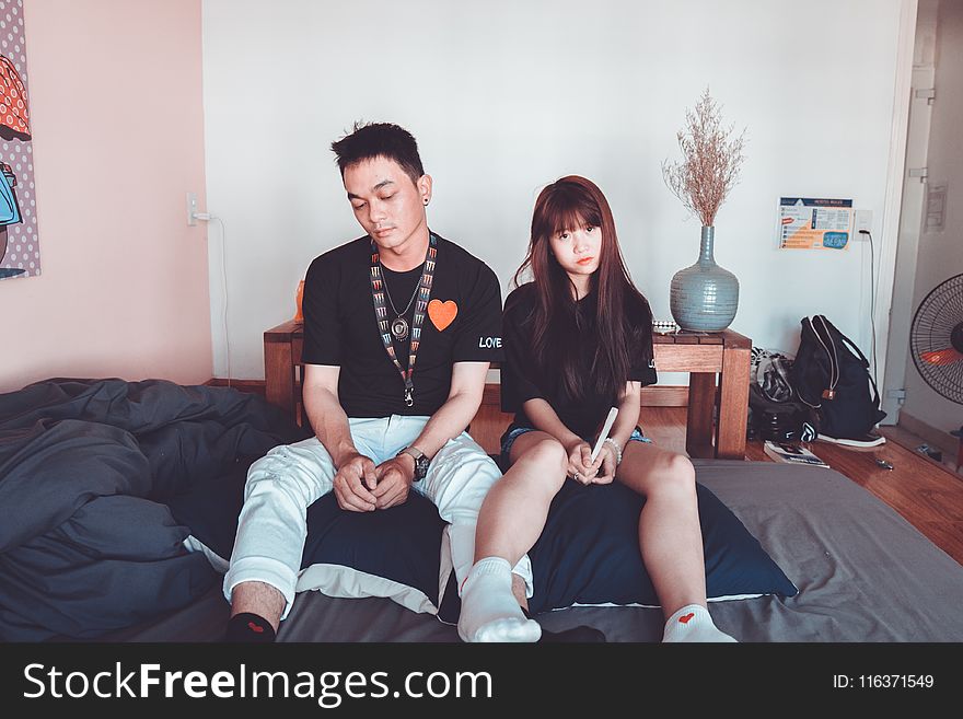 Man And Woman Wearing Black Shirts Sitting On Bed