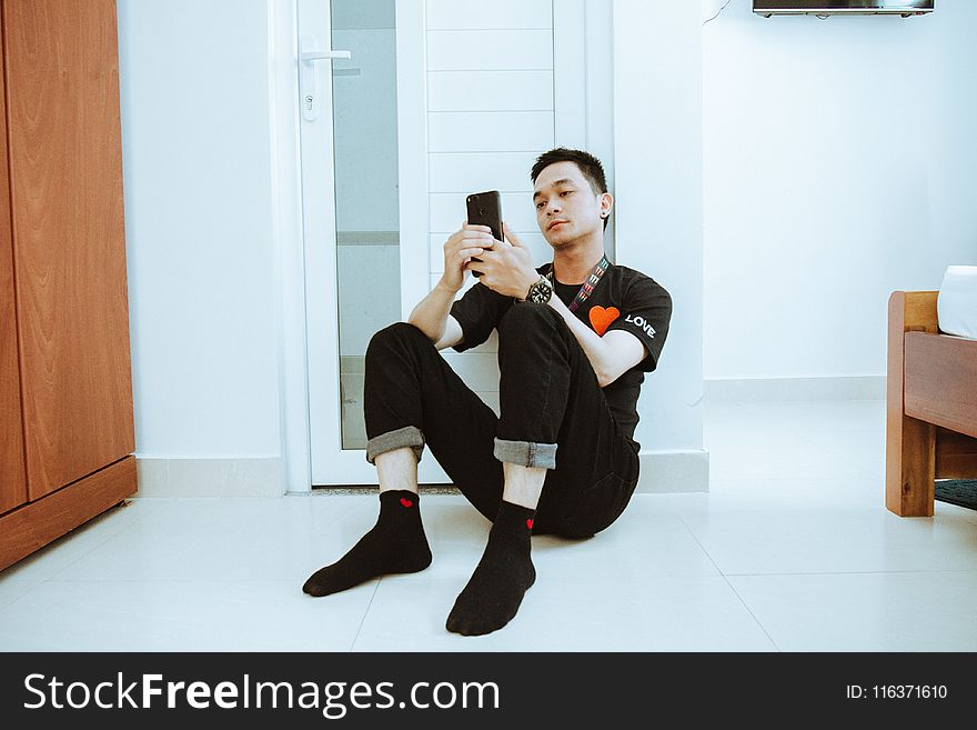 Man Leaning On Door While Holding On Smartphone