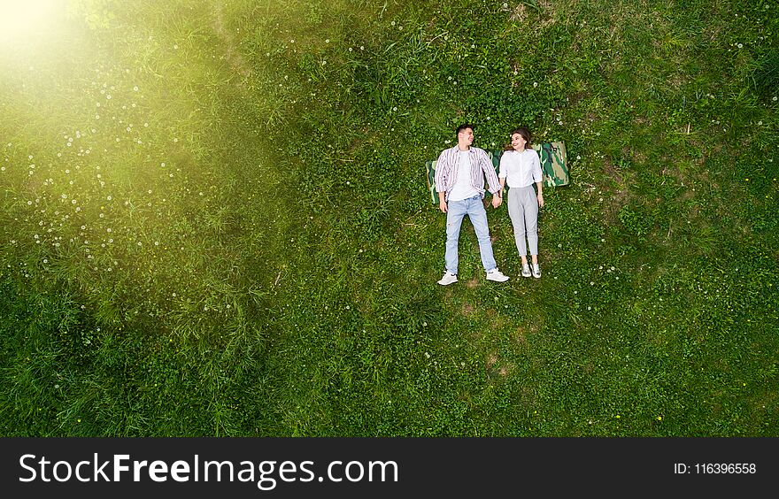 Beautiful In Love Young Couple Lying On The Grass, View From Above