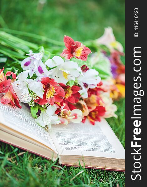 Beautiful flowers on the grass with a book. Close-up.