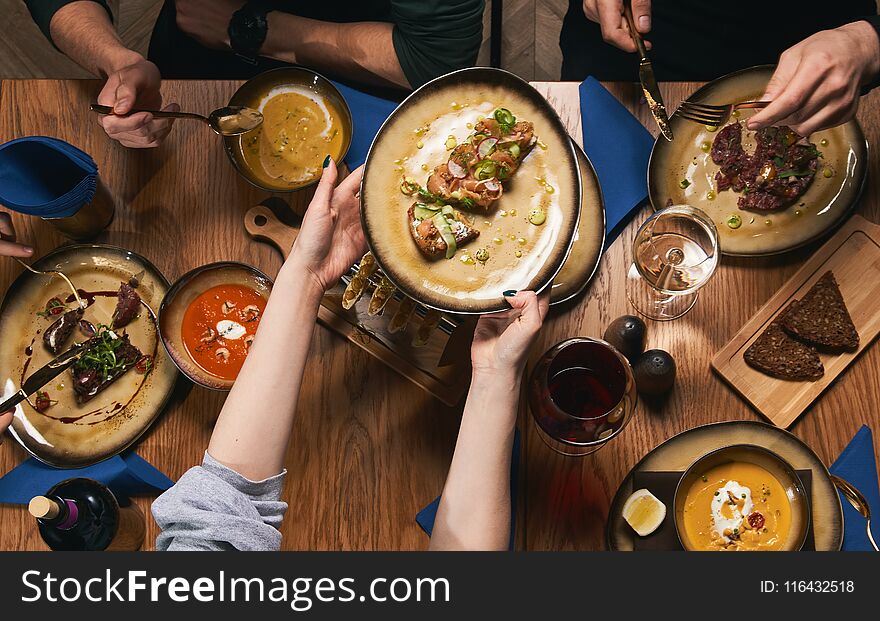 Table with food, top view. Flat-lay of friends hands eating and drinking together. People having party, gathering, celebrating together at wooden rustic table set with different wine and snacks