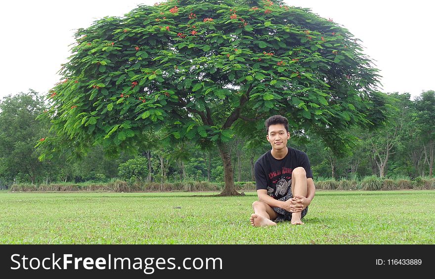 Man In Black Shirt Sitting On Grass Field