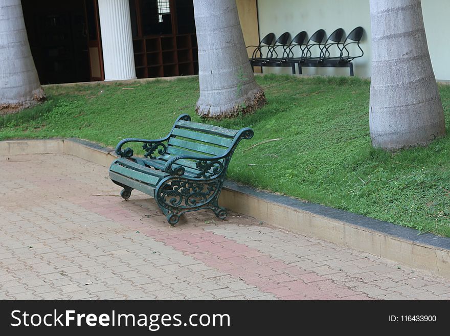 Green Metal Bench Beside Concrete Curb and Green Grass