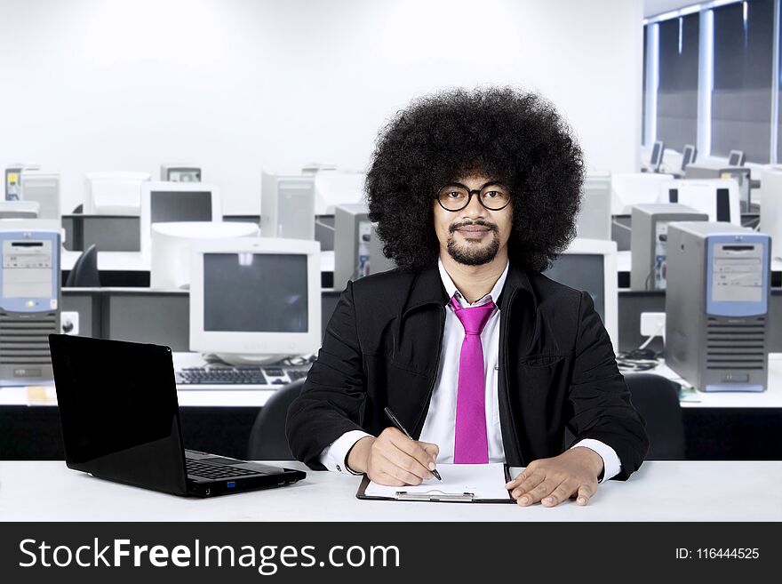 Afro businessman working in the office while wearing glasses and smiling at camera. Afro businessman working in the office while wearing glasses and smiling at camera