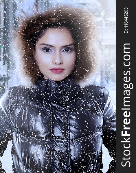 Closeup of beautiful Indian woman wearing winter jacket while looking at the camera under snowfall. Closeup of beautiful Indian woman wearing winter jacket while looking at the camera under snowfall