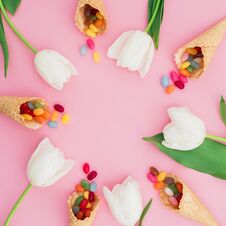 Frame Made Of Sugar Candy In Waffle Cones And White Tulip Flowers On Pink Background. Flat Lay, Top View Royalty Free Stock Photos