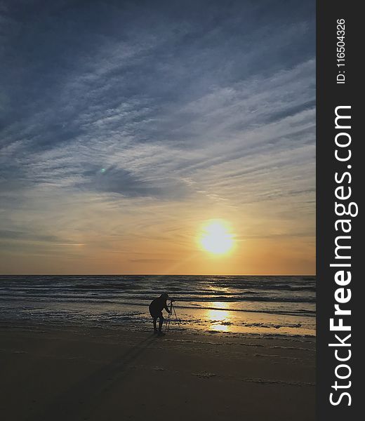 Silhouette Photo of Person Placing Tripod Stand on Seashore