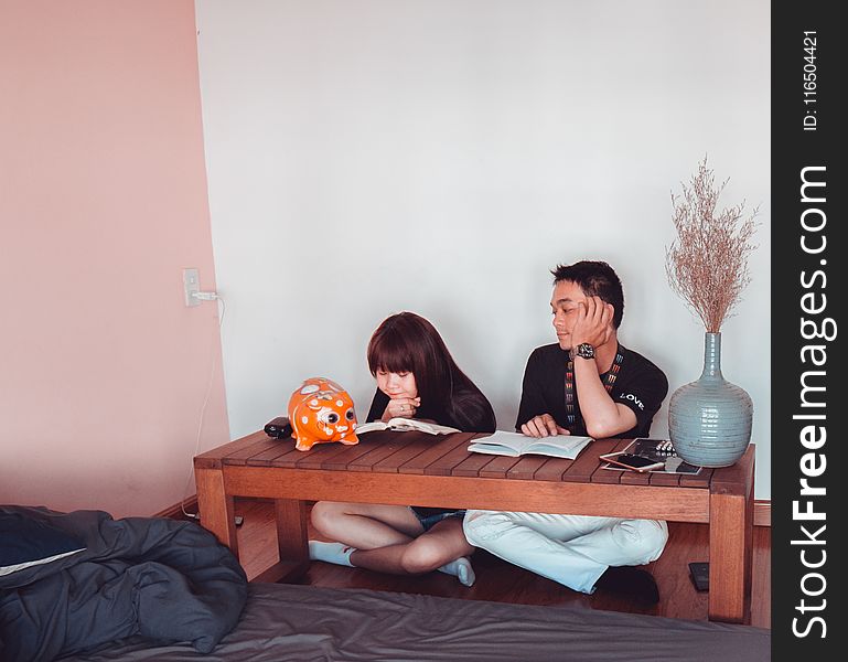 Girl and Boy Sitting in Front of Brown Wooden Coffee Table