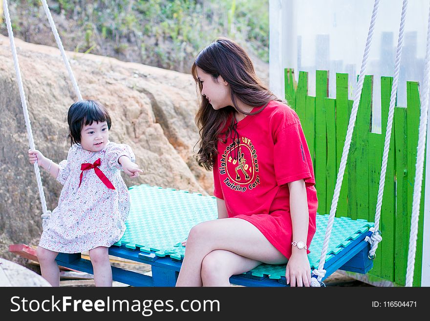 Woman Wearing Red Crew-neck Shirt Sitting on Swing Bench