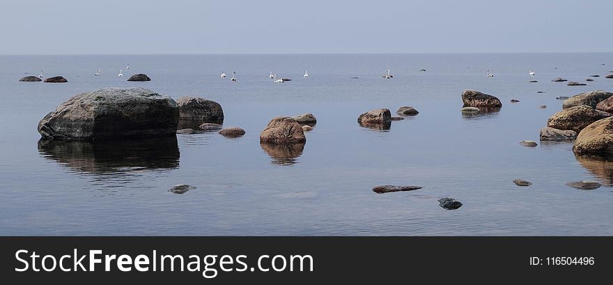 Photography of Brown Rocks Near Body of Water at Daytime