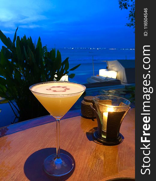 Orange Liquid in Clear Martini Glass on Brown Wooden Surface