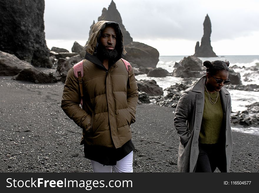 Man and Woman Wearing Jackets Walking on Shore
