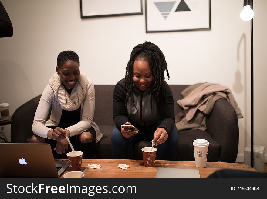 Woman in Black Jacket Sitting Beside Woman in White Sweater