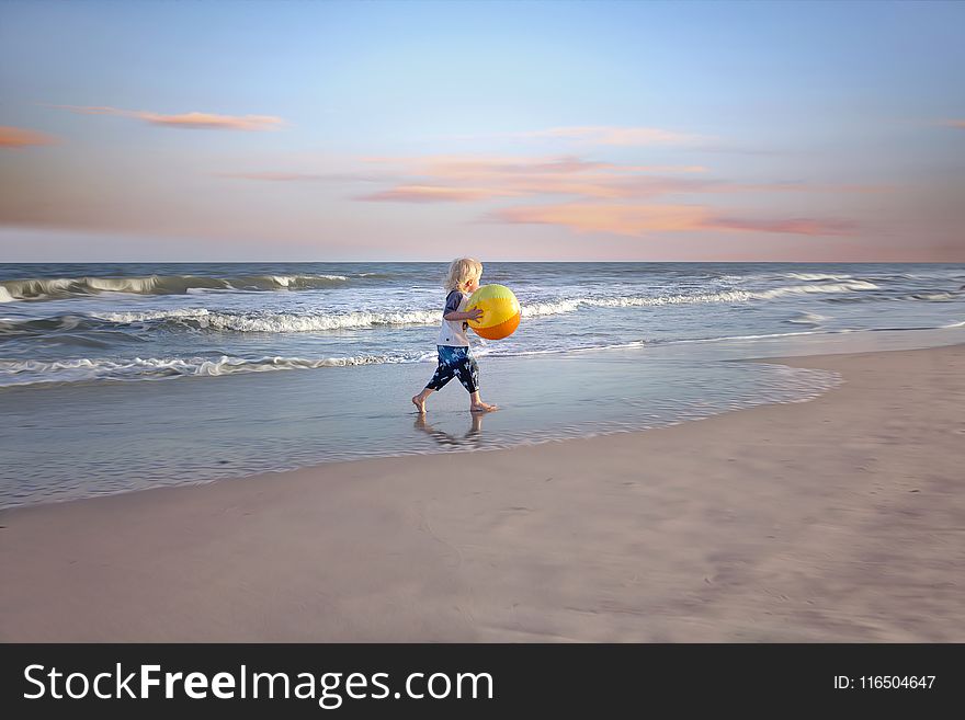 Boy Holding Ball Near Body of Water