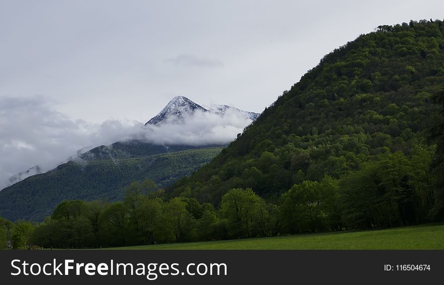 hill next to a mountain Surrounded by Clouds