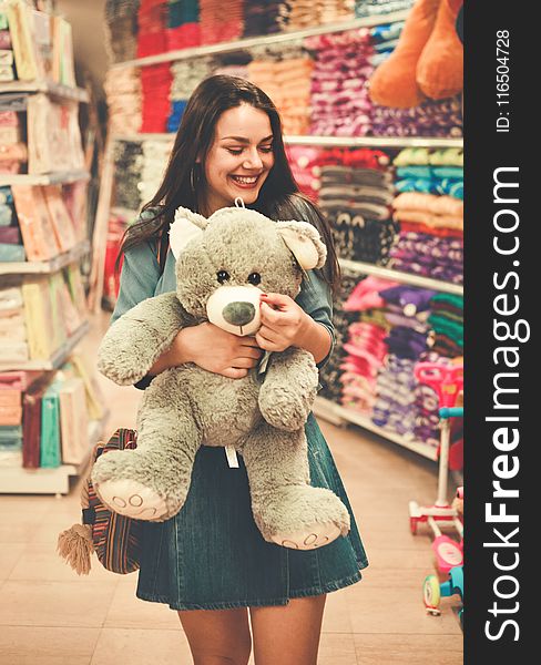 Woman Wearing Blue Top and Blue Denim Skirt Hugging a Brown Bear Plush Toy