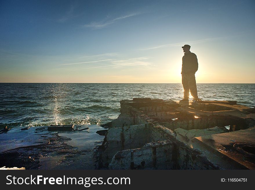 Silhouette Photo of Man Standing Near the Edge of Concrete Pavement