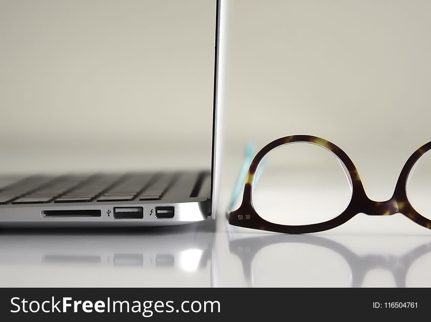 Black Framed Eyeglasses Beside Laptop Computer